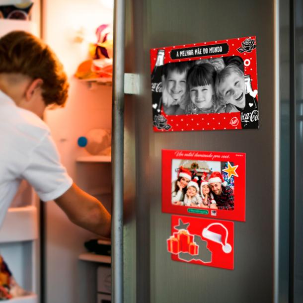 Homem abrindo geladeira que tem um porta-retratos magnéticos
